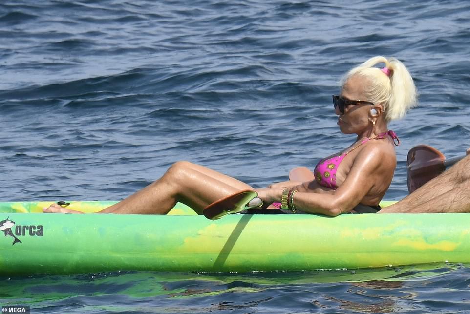 Relaxing: Donatella enjoyed a brief respite while out on the water, and took the opportunity to top up her tan