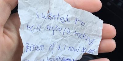 She buys homeless man meal & sits with him. He hands her crumpled note before leaving